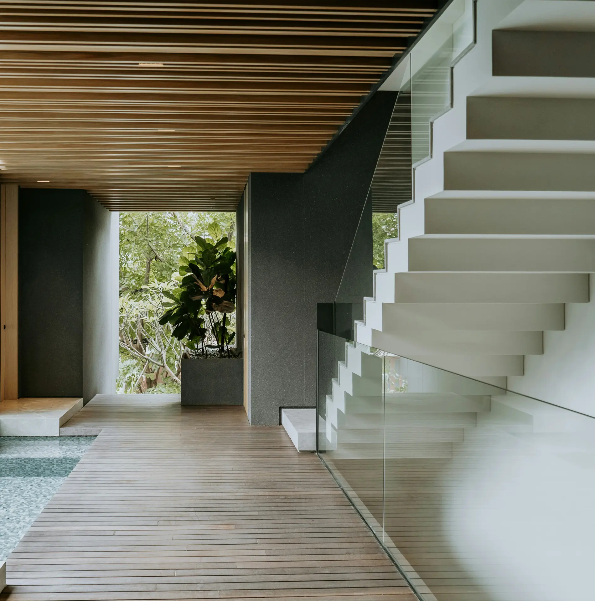 Indoor space featuring a timber-slatted ceiling, a decked wooden floor beside a narrow pool